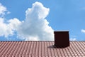 Red metal house roof tiles with brick roof chimney against blue sky background Royalty Free Stock Photo