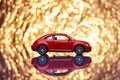 Red metal model car with fancy shiny gold background full of sparks out of focus.