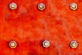 Red metal plate painted with strong red and orange colours and fixed with six large steel bolt screws as texture background Royalty Free Stock Photo