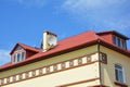 Red metal roof house construction with attic room, mansard window, rain gutter and roofing problem area. Royalty Free Stock Photo