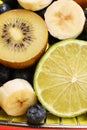 Red metal shopping basket full of fruits and berries close up isolated on a yellow background. Lime, banana, blueberries, kiwi Royalty Free Stock Photo