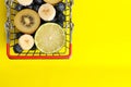 Red metal shopping basket full of fruits and berries isolated on a yellow background. Lime, banana, blueberries, kiwi and apples Royalty Free Stock Photo