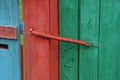 Red metal spring closer on green wooden fence boards