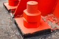 The red metal support is bolted to the concrete base with large bolts. Fixing a tower or tower to the ground. Royalty Free Stock Photo