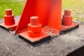 The red metal support is bolted to the concrete base with large bolts. Fixing a tower or tower to the ground. Royalty Free Stock Photo