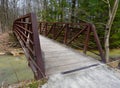 Red metal and wooden bridge over a creek in a forest. Royalty Free Stock Photo