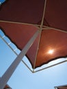 Red metallic parasol beach umbrella over blue sky