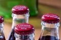 Red metals caps on the top of retro style coca cola bottles carrying the message `Please recycle me`.