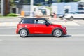 red Mini Cooper on the city road. Fast moving car on Moscow streets. Vehicle driving along the street in city with blurred