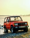 Red Mitsubishi Shogun MK1 getting out of the body water at dusk