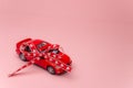 Red model car with bow on a pink background. Car as gift, surprise. Royalty Free Stock Photo