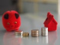 Many coins are stacked rows orderly reflection on blurred background and red pig coin bank, piggy bank, money box and red model ho Royalty Free Stock Photo