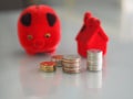 Many coins are stacked rows orderly reflection on blurred background and red pig coin bank, piggy bank, money box and red model ho Royalty Free Stock Photo