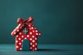 Red model house with dots and glitter bow sitting on blue surface Royalty Free Stock Photo