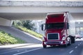 Red modern semi truck with reefer trailer under bridge Royalty Free Stock Photo