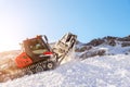 Red modern snowcat ratrack with snowplow snow grooming machine preparing ski slope piste hill at alpine skiing winter resort Royalty Free Stock Photo