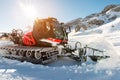 Red modern snowcat ratrack with snowplow snow grooming machine preparing ski slope piste hill at alpine skiing winter Royalty Free Stock Photo