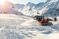 Red modern snowcat ratrack with snowplow snow grooming machine preparing ski slope piste hill at alpine skiing winter Royalty Free Stock Photo