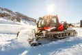 Red modern snowcat ratrack with snowplow snow grooming machine preparing ski slope piste hill at alpine skiing winter