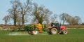 Red modern tractor pulling a crop sprayer