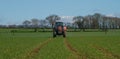 Red modern tractor pulling a crop sprayer