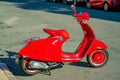 Red motor bike or scooter with electric battery and tires with metal kick stand on the city street downtown for transportation Royalty Free Stock Photo