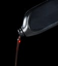 Red motor oil lube pouring from black plastic bottle Royalty Free Stock Photo