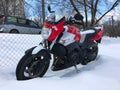 Red motorcycle stands in a snowy parking lot covered in snow in winter Royalty Free Stock Photo