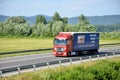 Red moving Mercedes-Benz Actros truck coupled with semi-trailer located on slovak D1 highway surrounded by green field and trees. Royalty Free Stock Photo