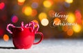 Red mug with candy canes in snow with defocussed fairy lights, bokeh in the background, Festive Christmas background Royalty Free Stock Photo