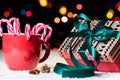 Red mug with candy canes in snow with nicely wrapped present