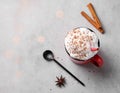 Red mug with hot chocolate or cocoa with whipped cream, with spoon, cinnamon sticks and star anise