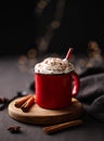 Red mug with hot chocolate or cocoa with whipped cream on a wooden stand with cinnamon sticks and star anise