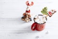 Red mug of hot chocolate with marshmallows and cookies, toy reindeer on a sleigh ,red Christmas balls on a white  wooden Royalty Free Stock Photo