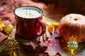 Red mug hot chocolate with marshmallows on table with maple leaves, garlands, cinnamon sticks. Autumn atmosphere, warming coffee,