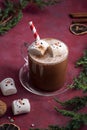 Red mug with hot chocolate and melted marshmallow snowman, red festive background