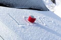 A red mug with a hot drink on a snowy car hood on a bright winter sunny day. The inscription on the snow is love Royalty Free Stock Photo