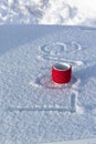 A red mug with a hot drink on a snowy car hood on a bright winter sunny day. The inscription on the snow is love. Selective focus. Royalty Free Stock Photo