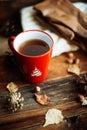 Hands in red knitted gloves holding a hot cup of coffee against yellow leaves background. Concept of autumn time, warmth and cozin Royalty Free Stock Photo