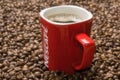 Red mug of Nescafe on the background of scattered coffee beans