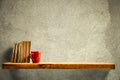 Red mug and old books on wooden shelf. Copy empty space for your decoration and products. Beige brown retro wall background. Royalty Free Stock Photo