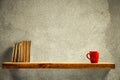 Red mug and old books on wooden shelf. Copy empty space for your decoration and products. Beige brown retro wall background. Royalty Free Stock Photo