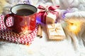 Red mug with tea in Christmas decorations on a white knitted blanket. New year, garlands, gifts, cinnamon and dried orange - an at Royalty Free Stock Photo