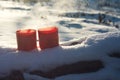 Red mugs with a hot drink soar in the cold, mugs in the snow on a Sunny frosty day, picnic in the winter campaign