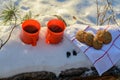 Red mugs with a hot drink soar in the cold, mugs in the snow on a Sunny frosty day, picnic in the winter