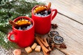 Red mugs of hot mulled wine with spices and Christmas tree branches covered with snow. Copy space for text. Royalty Free Stock Photo