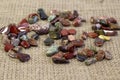 Red and multicolored jasper polished tumblestones as nice natural background on rough linen