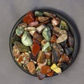 Red and multicolored jasper polished tumblestones on black plate and grey cloth