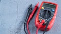 Red multimeter or a multitester, also known as a VOM on gray table. Electronic measuring instrument. Red and black wires Royalty Free Stock Photo