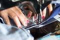 Red nail hand sewing jeans repair.